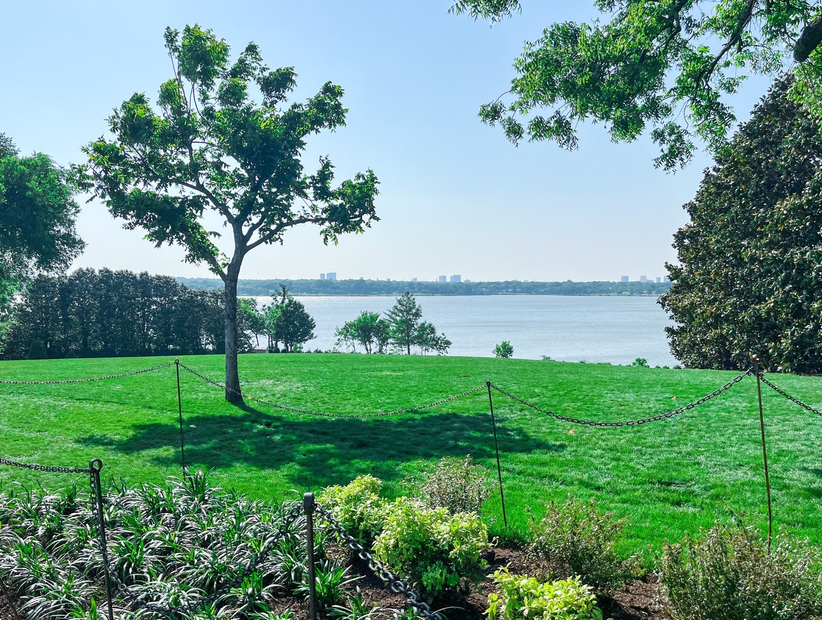 Green lawn and trees by White Rock Lake with Dallas in the distance