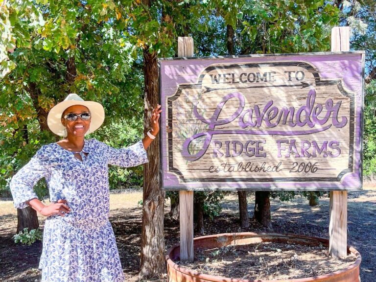 A woman standing next to a sign that reads “Lavender Ridge Farms.”