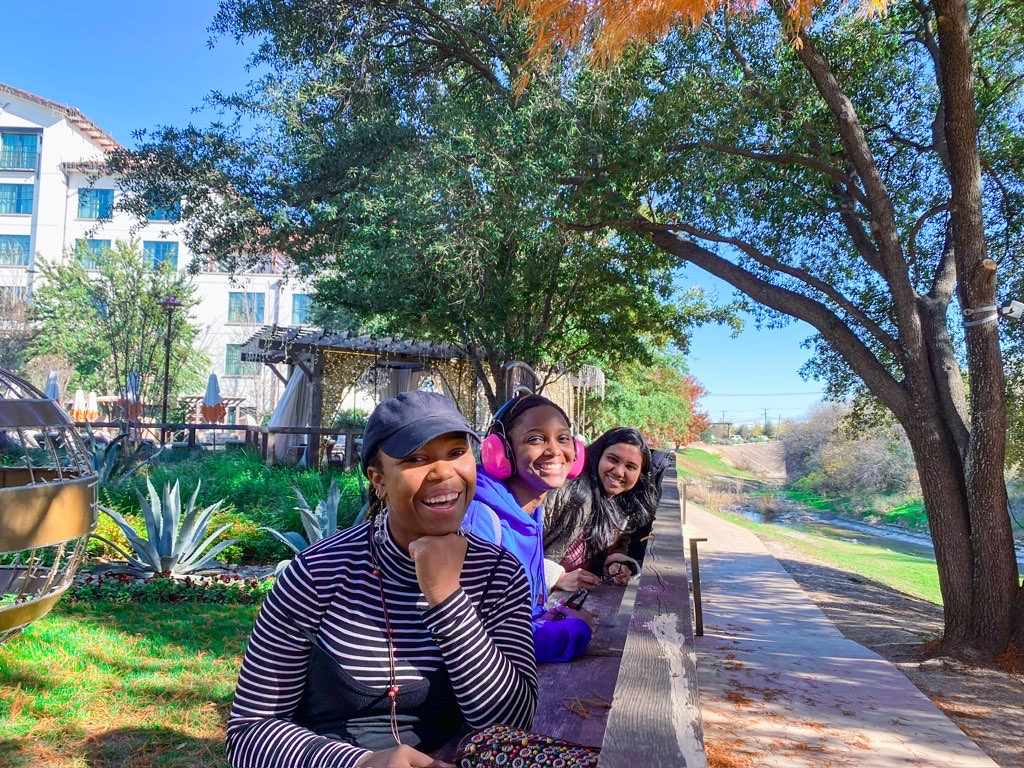 Three friends posing by fence at Fort Worth Stockyards on a Dallas itinerary