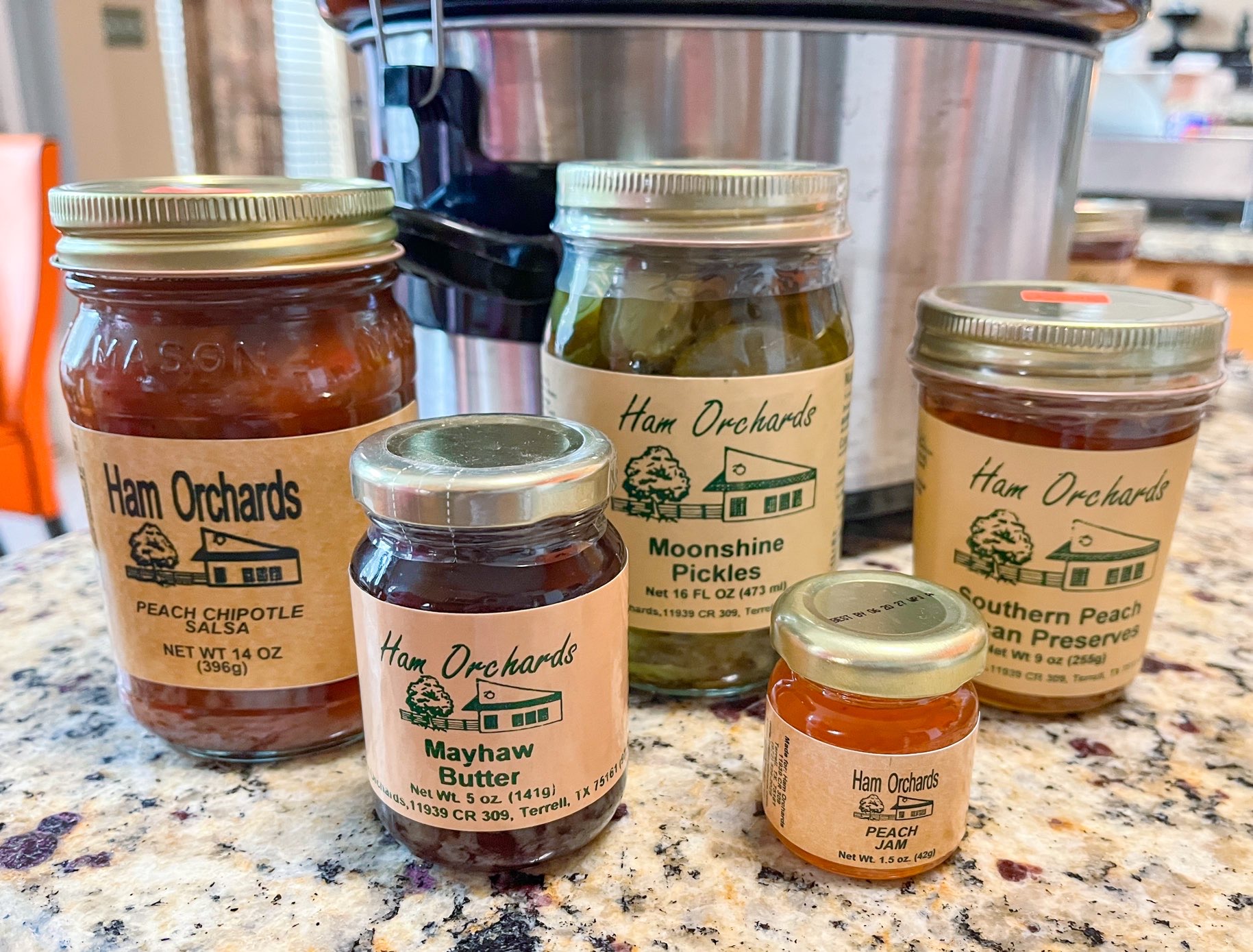 Bottled products including mayhaw butter, moonshine pickles, and peach chipotle salsa for sale at Ham Orchards, one of the Dallas Farms near Dallas, Texas.