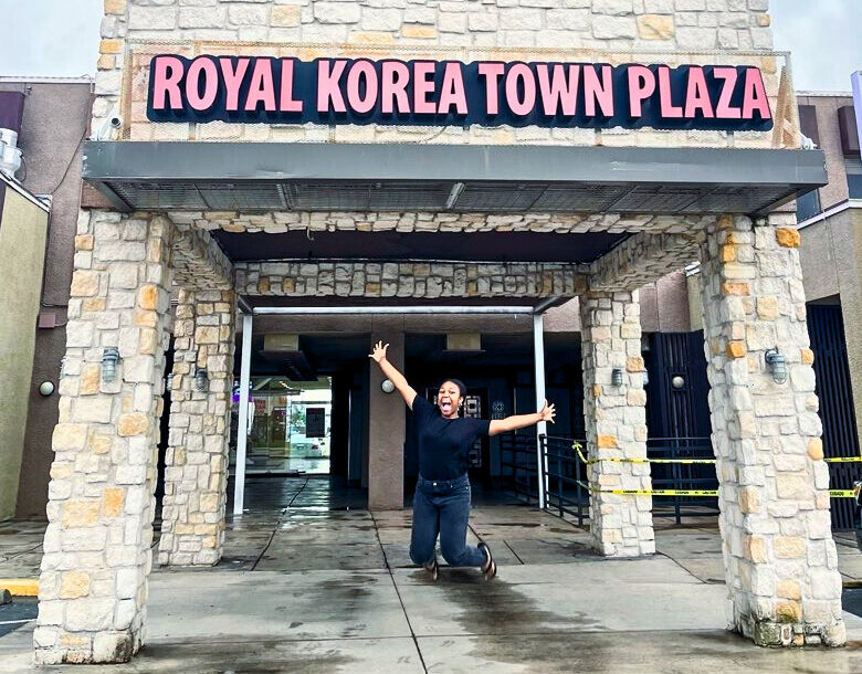 A Dallasite leaps with joy in front of Royal Korea Town Plaza in Dallas’ original Koreatown, one of the unique-things-to-do-in-dfw.