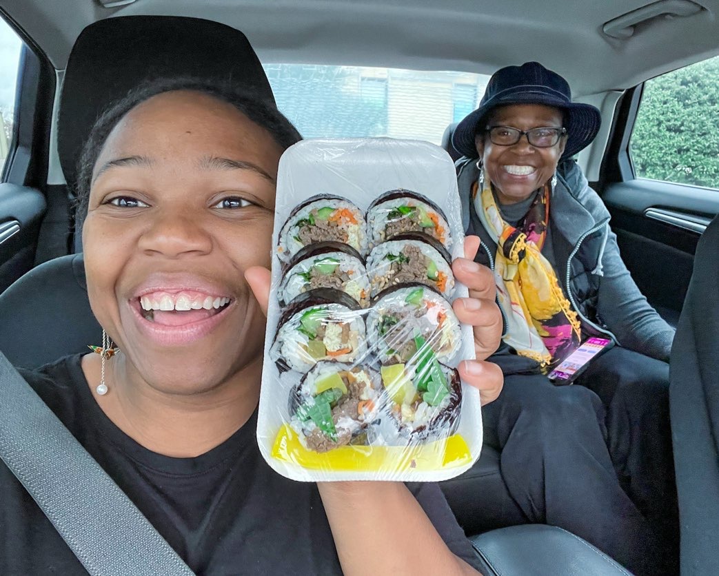 young lady happily holding package of freshly made gimbap in Dallas Koreatown
