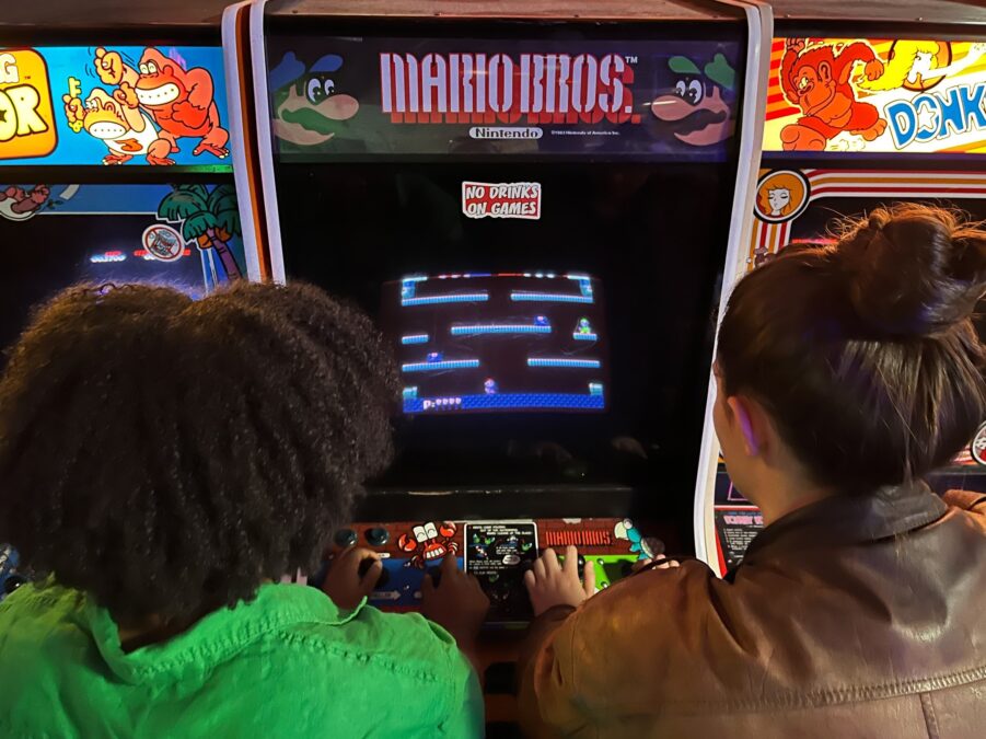 friends playing arcade game together at dallas arcade bar