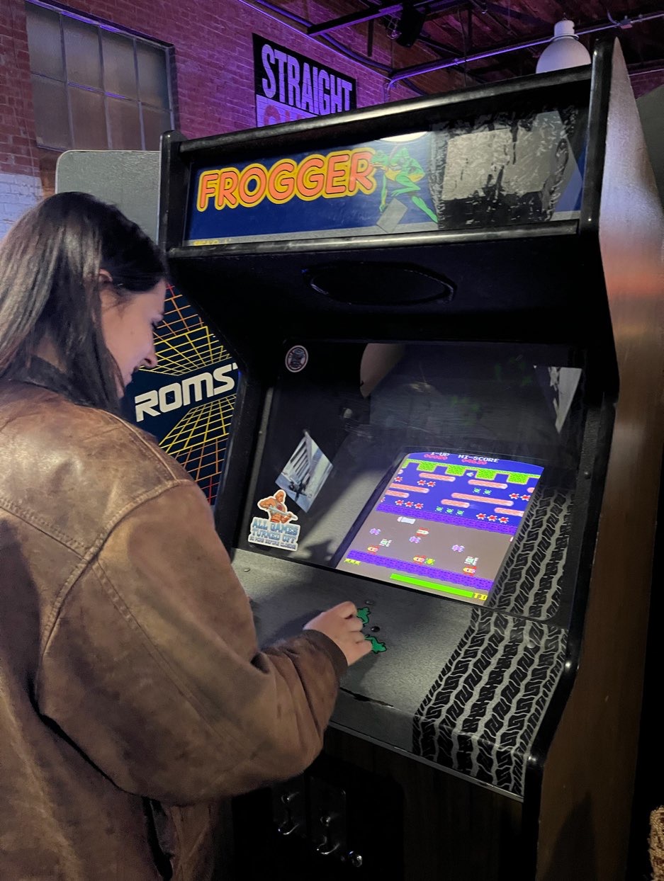young lady play Frogger video game at dallas arcade bar