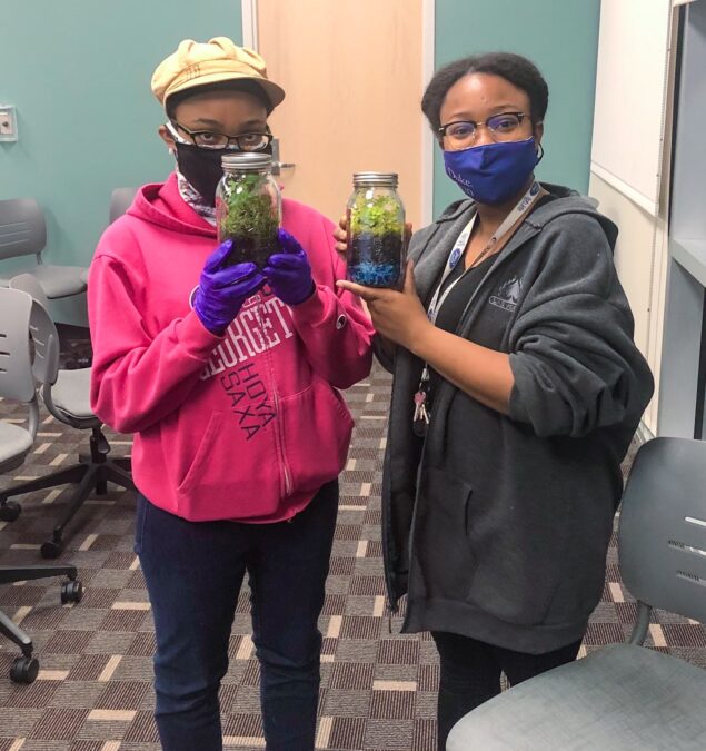 two young ladies holdng up completed terrarium projects made at the Lewisville branch library