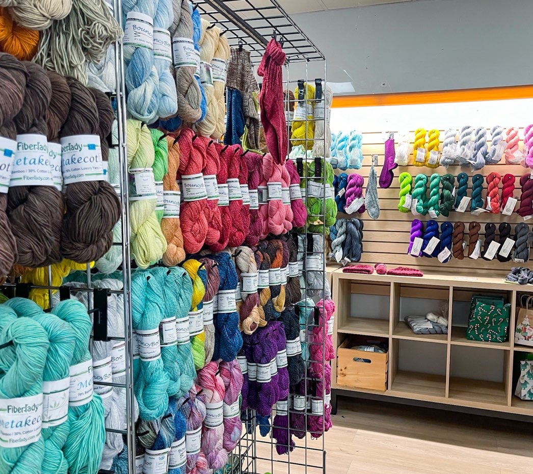 Rack of multi colored yarns hanging from rack at fiberlady; Dfw fiber fest