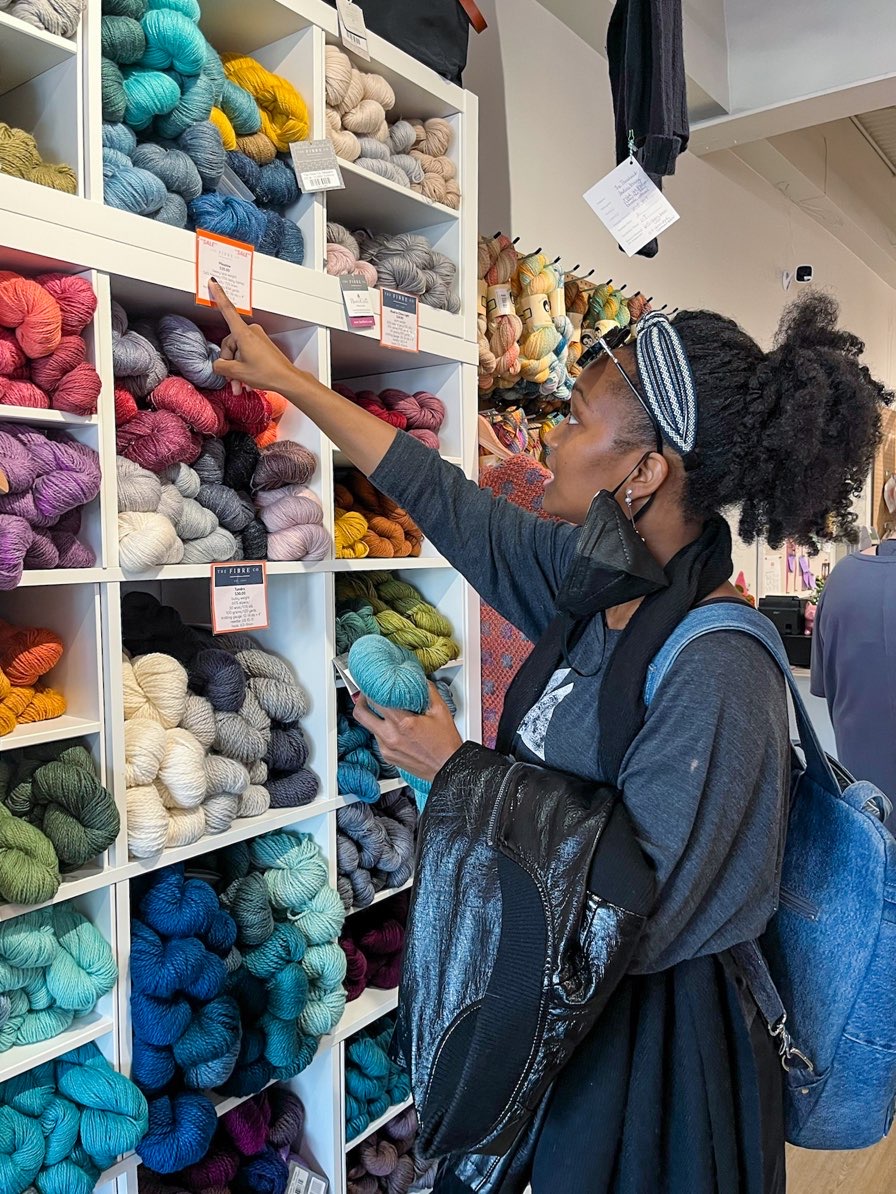 young lady looking at bank of yarn at yarn crawl