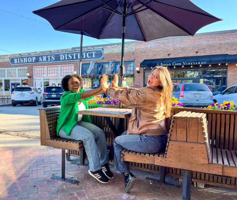 Two ladies happy and sitting at picnic table in the bishop arts district. Why texas is worth visiting.
