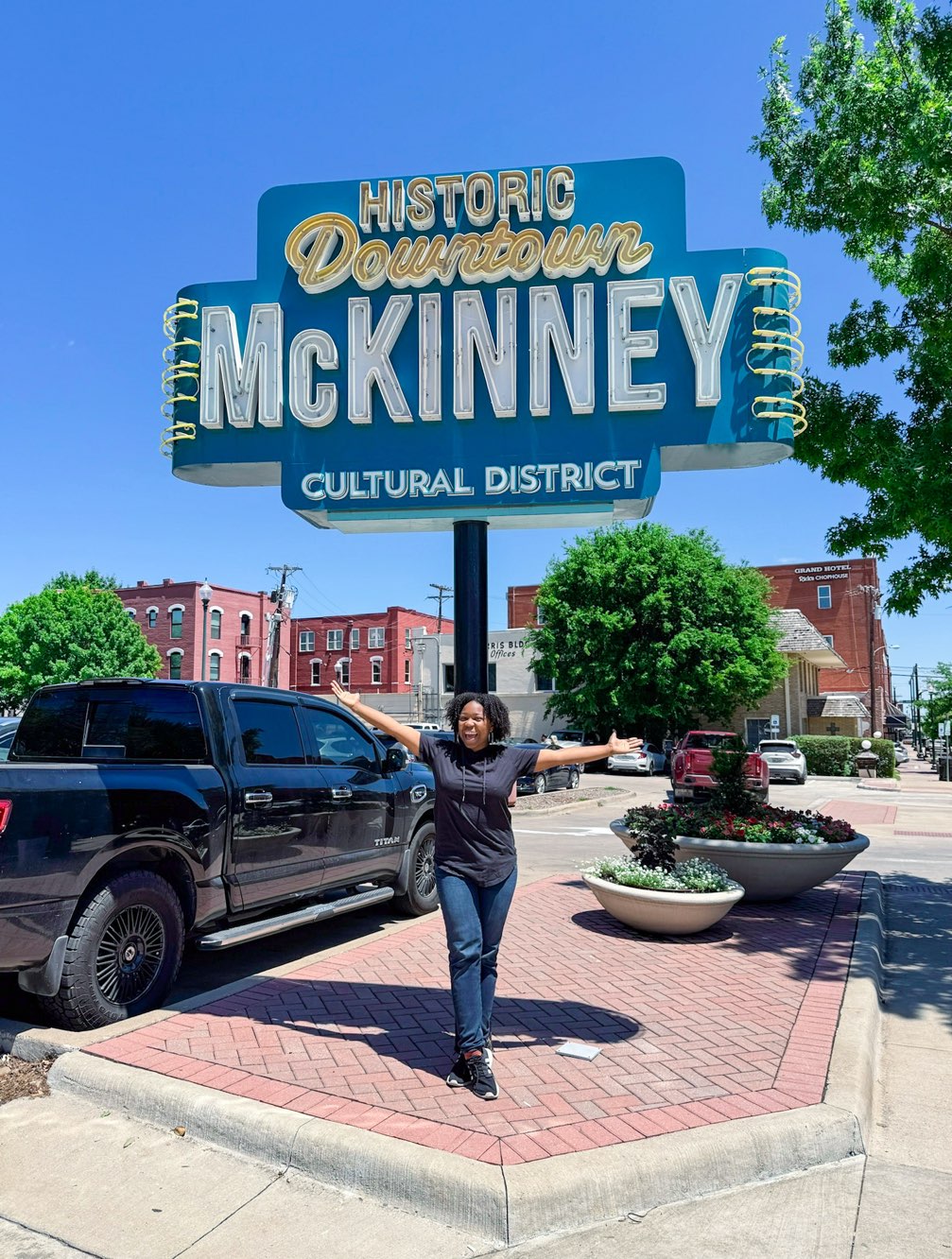Young lady standing in front of downtown  McKinney sign. Another reason why dallas is worth visiting.