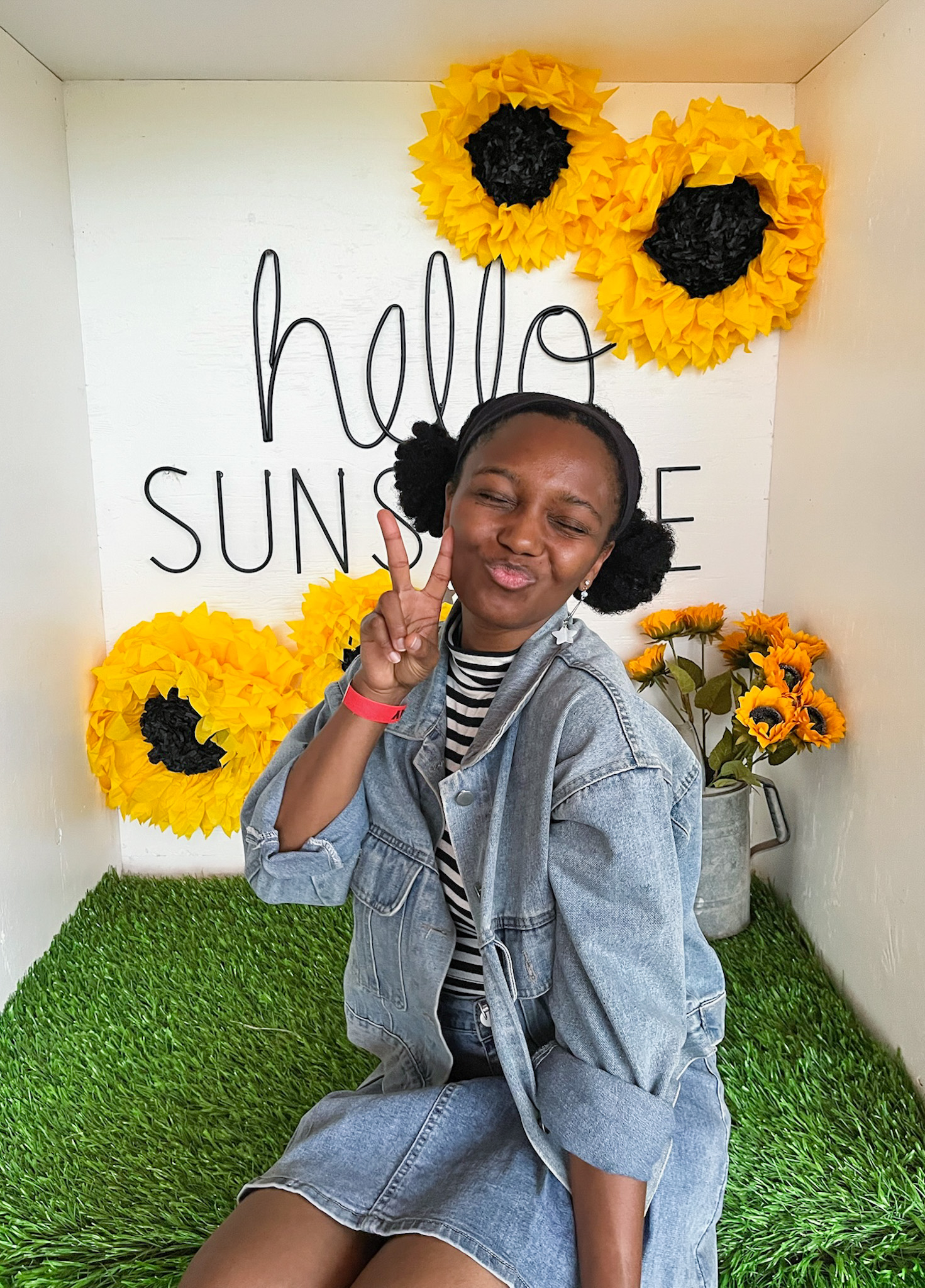 A woman flashing a peace sign at the camera at a sunflower field near Dallas.