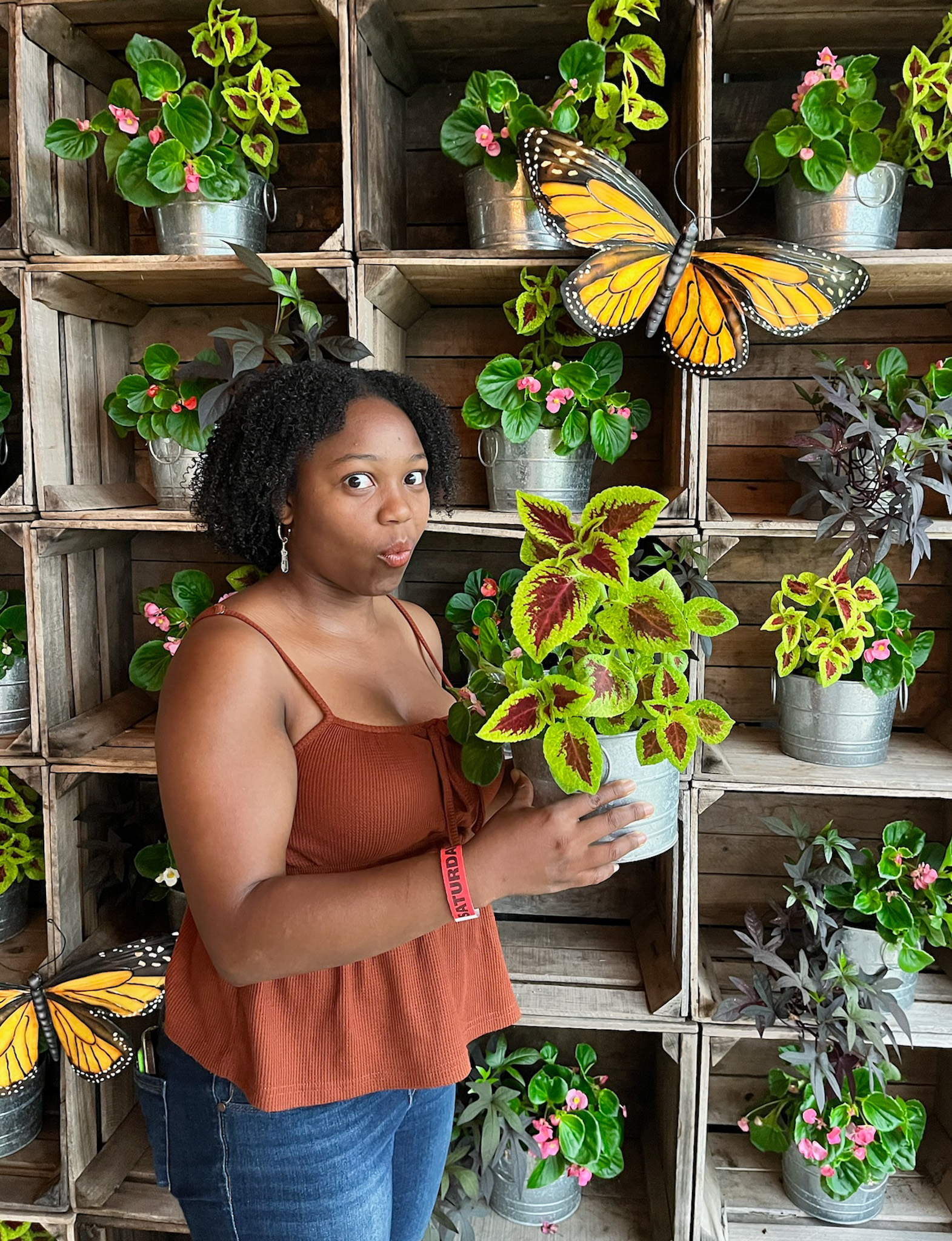 A woman holding a potted plant while looking at it.