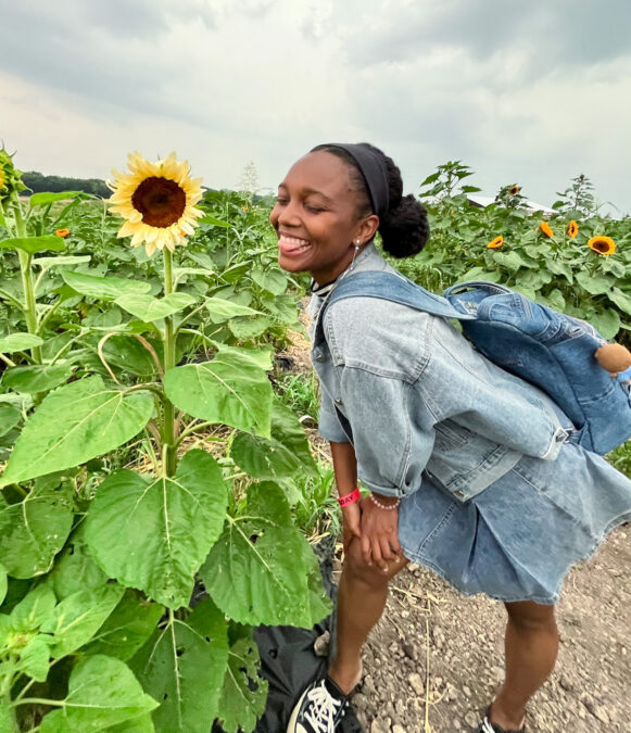A woman sticking out her tongue while standing among sunflowers at a sunflower field near Dallas.