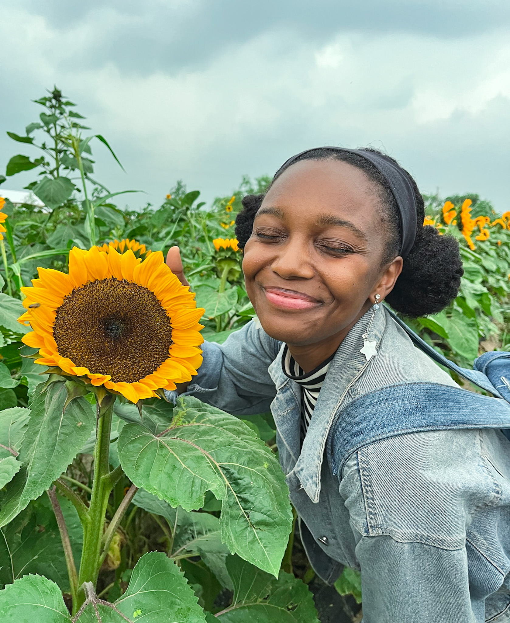 A woman smiling among blooming sunflowers.