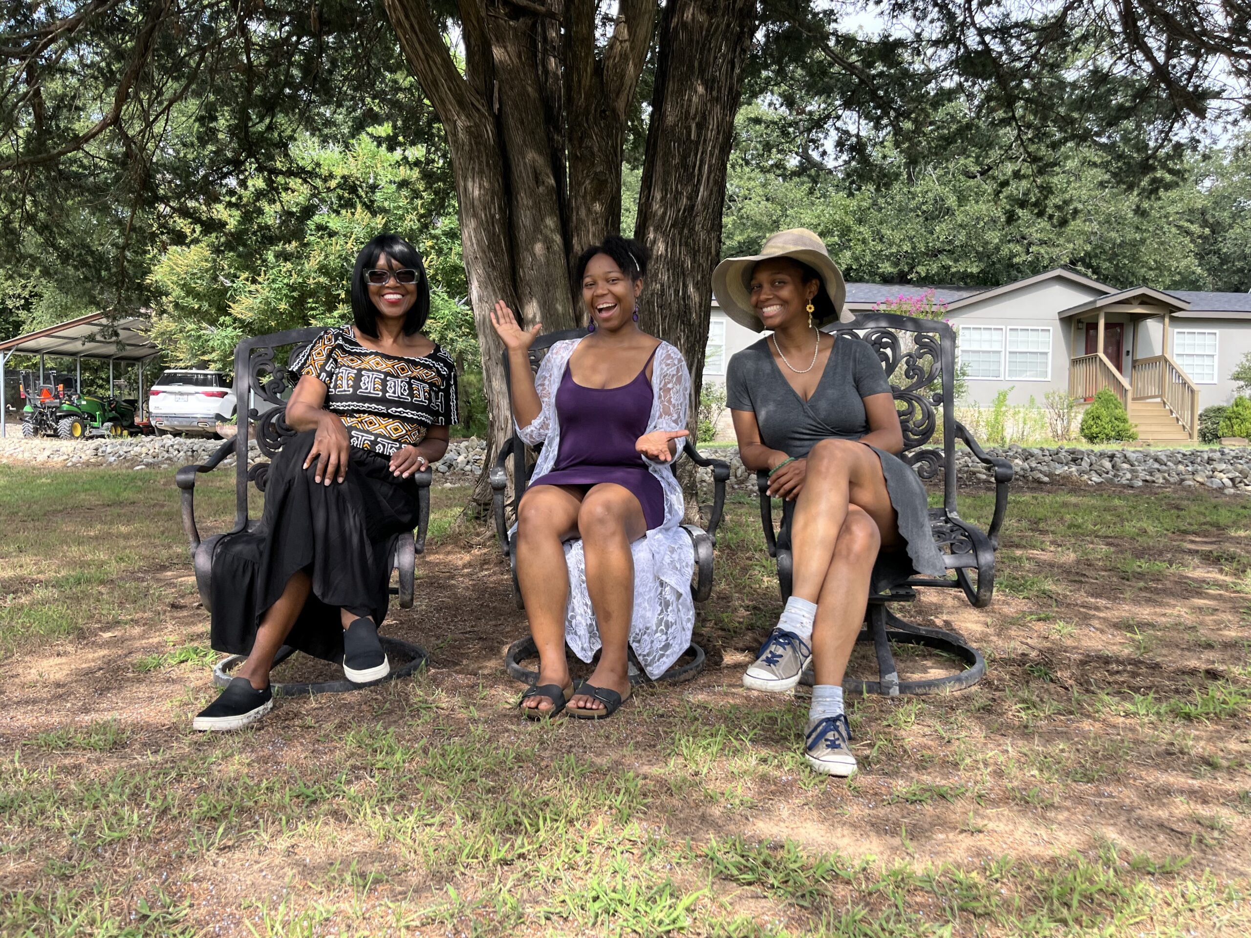 A mother and two daughters sitting together beneath a large tree at Lavender Ridge Farms.