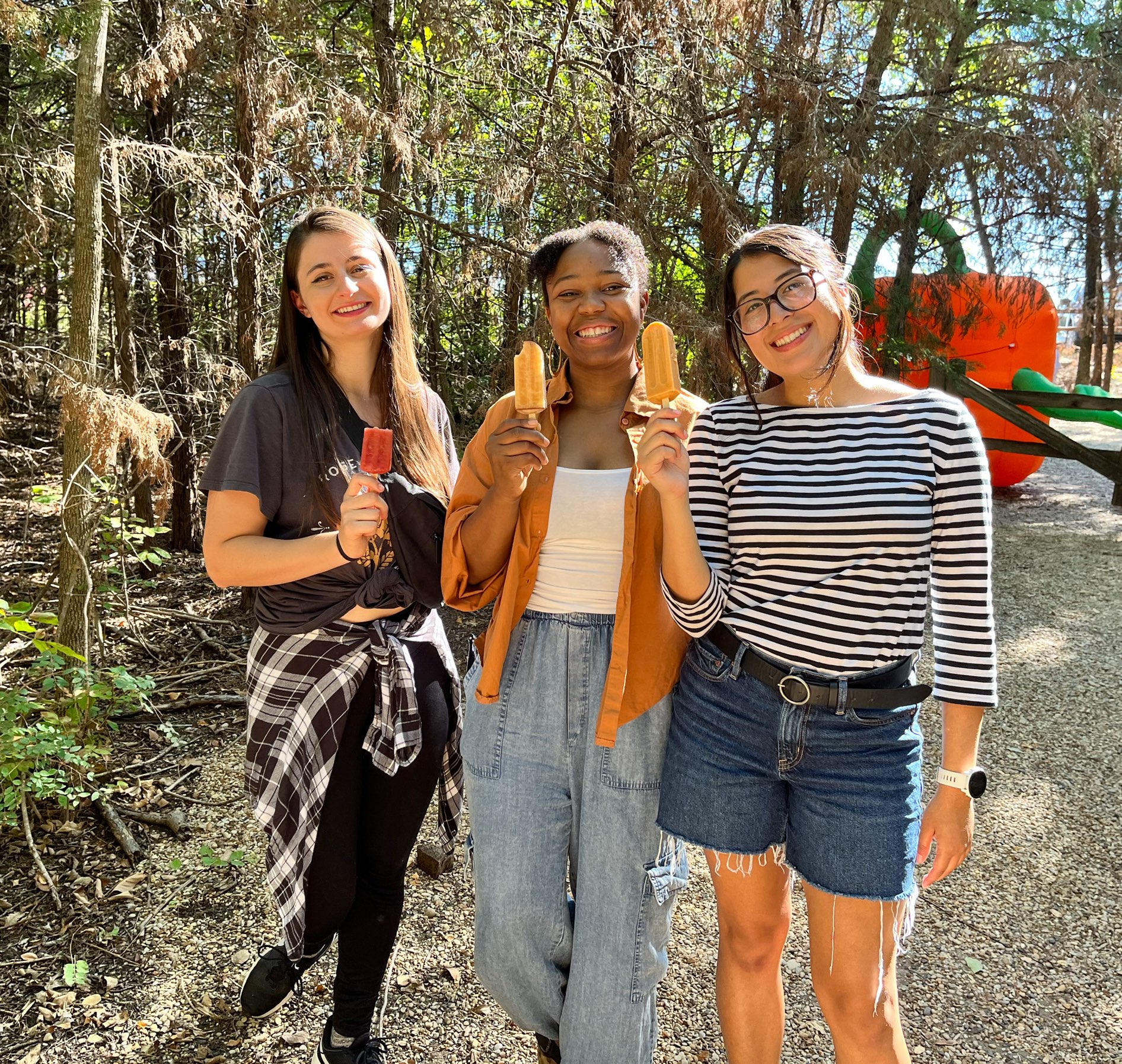 Three smiling young ladies holding popsicles at Blase Family Farm Pumpkin Patch, one of the many Dallas Farms near Dallas, Texas.