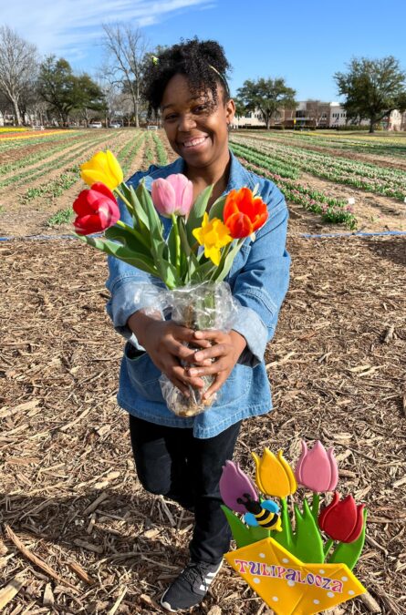 Young lady posing with a bunch of colorful tulips at a tulip farm.
