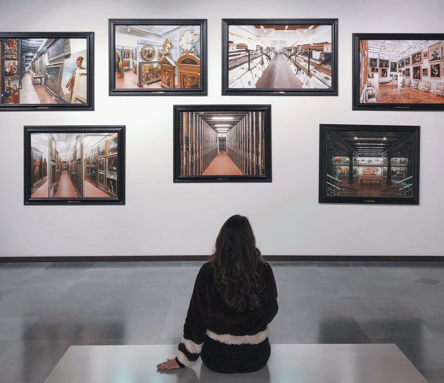 Young lady sitting on a bench viewing a clustered photo display of paintings at the Dallas Museum of Art, one of the free things to do in Dallas with kids.