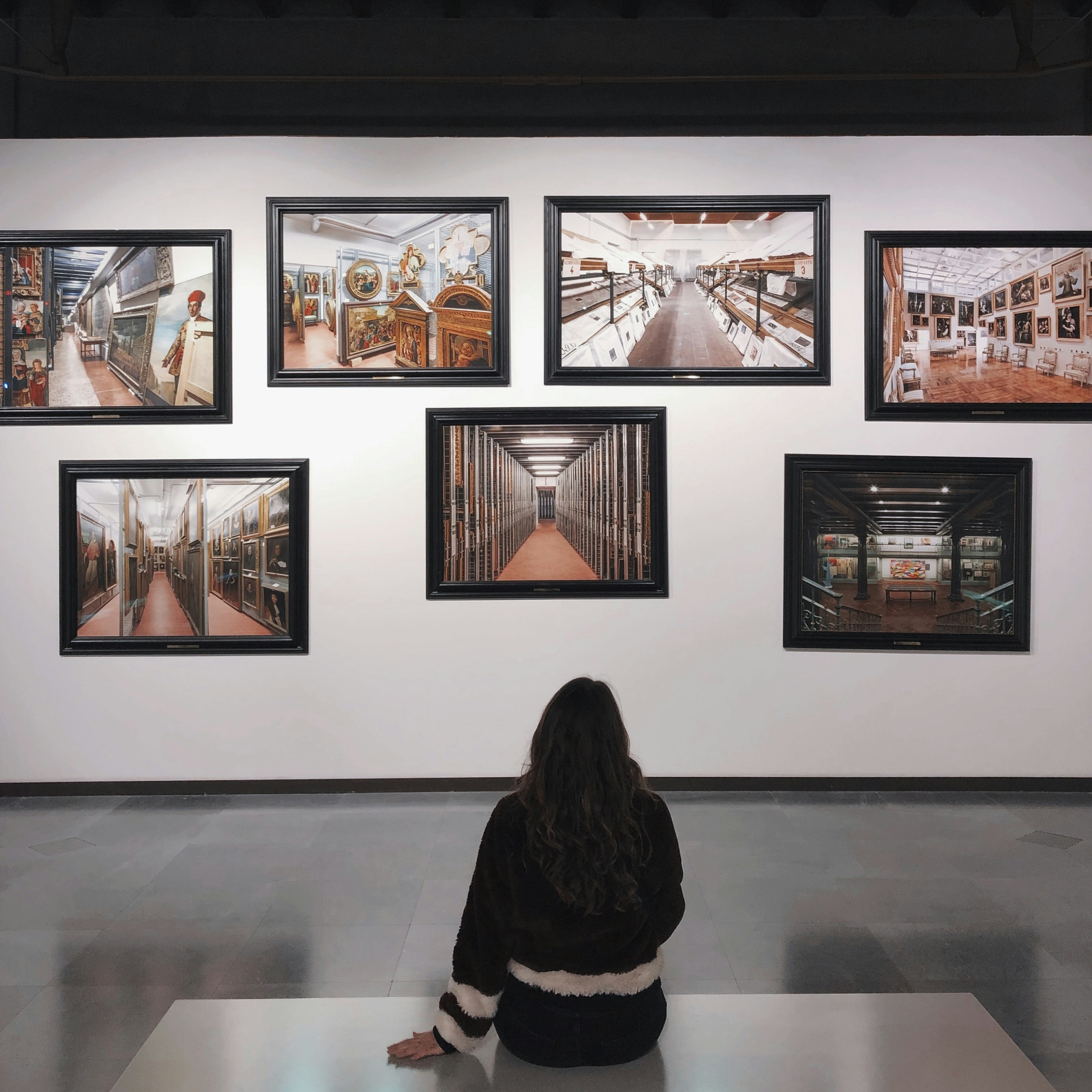 Young lady sitting on a bench viewing a clustered photo display of paintings at the Dallas Museum of Art, one of the free museums in Dallas.