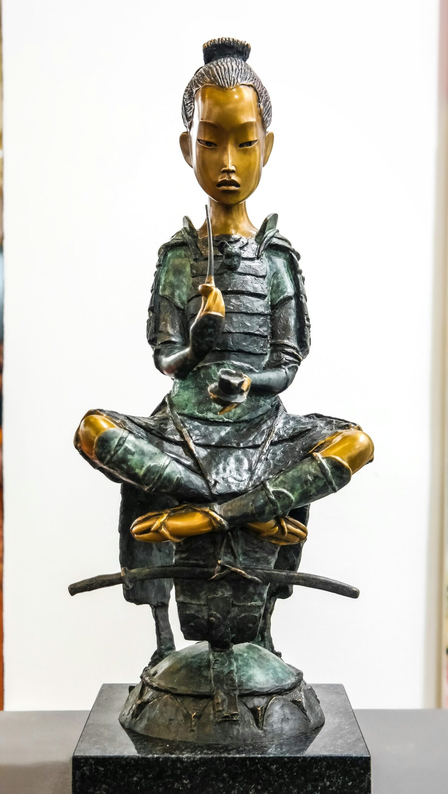 Gold and green samurai figurine sitting cross-legged in a meditative pose at the Samurai Collection, one of the free things to do in Dallas with kids.