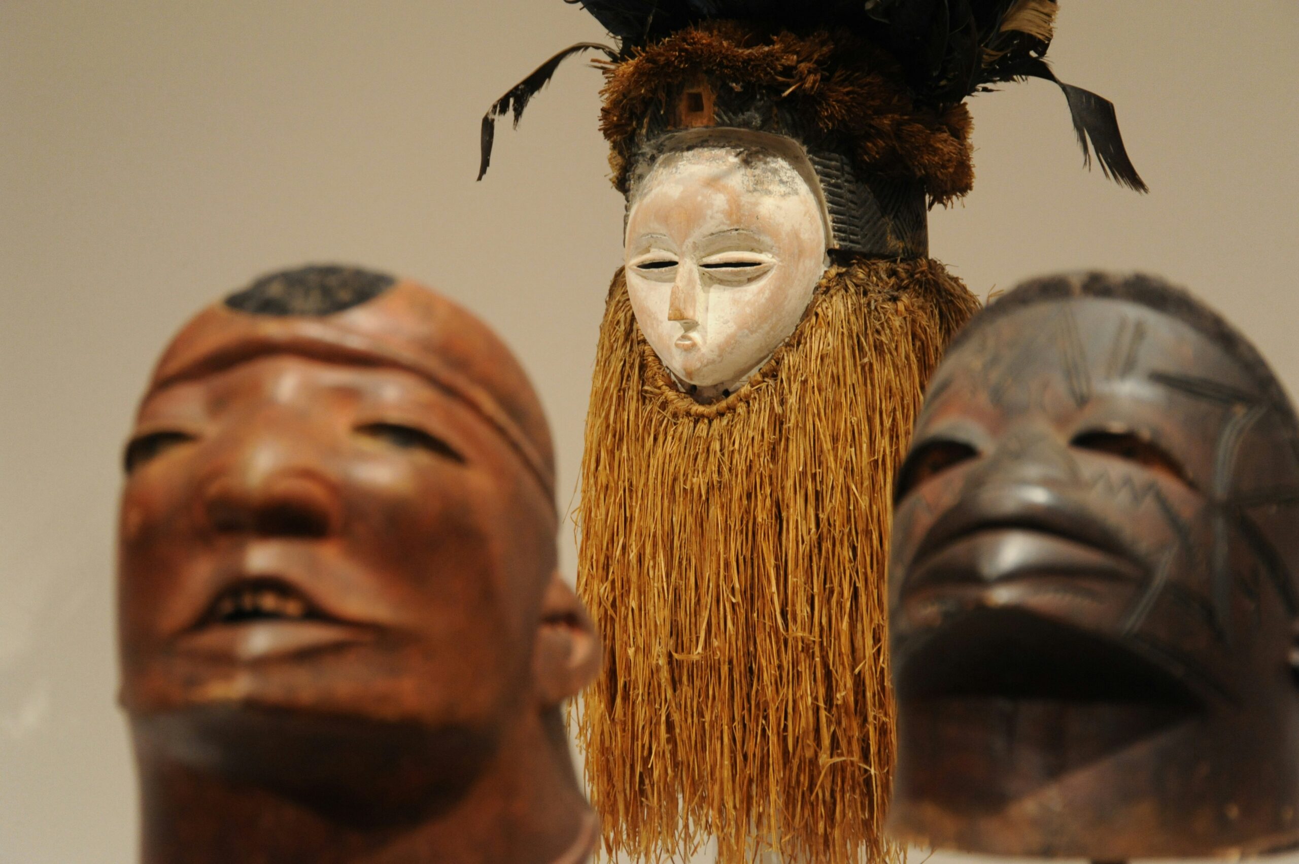 Three carved African masks with distinctive features in black, burnished red, and off-white at the African American Museum of Dallas, one of the free things to do in Dallas with kids.