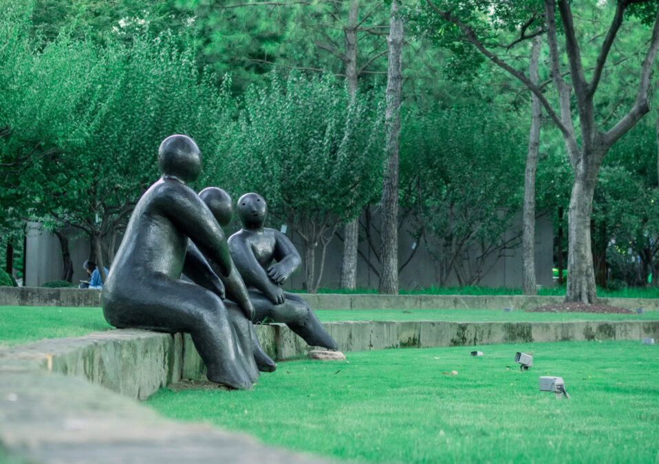 carved statues of three human forms sitting on low wall at Nasher Sculpture Center - one of the many free museums in Dallas