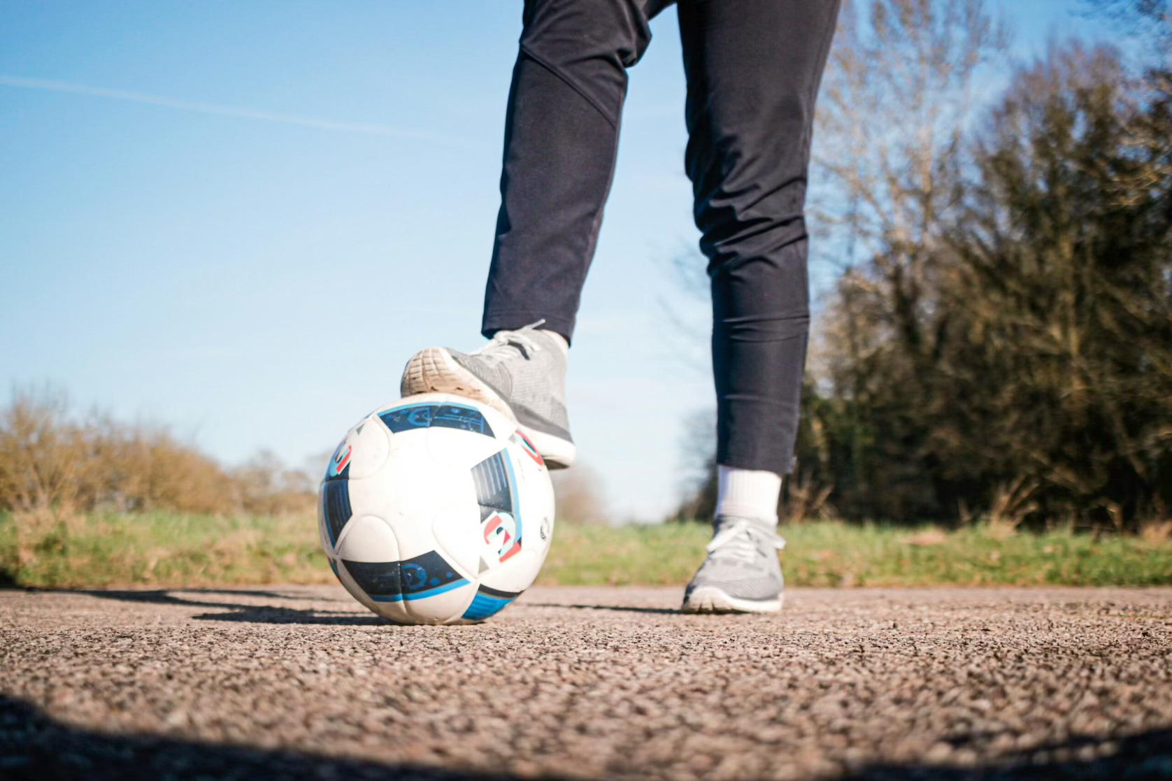Person in sneakers with foot on a kickball, representing Dallas sports leagues and adult kickball leagues in Dallas
