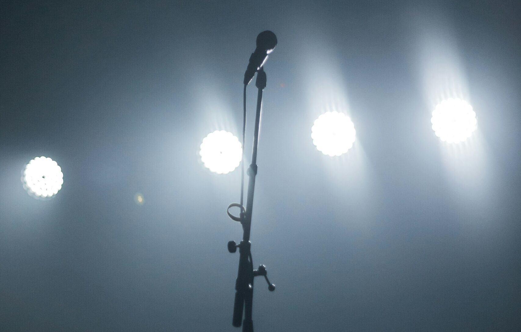 A lone microphone is centered on stage, illuminated by four bright lights pointed toward it to highlight the upcoming comedic performance, one of the free things to do in Dallas at night - every Tuesday night.