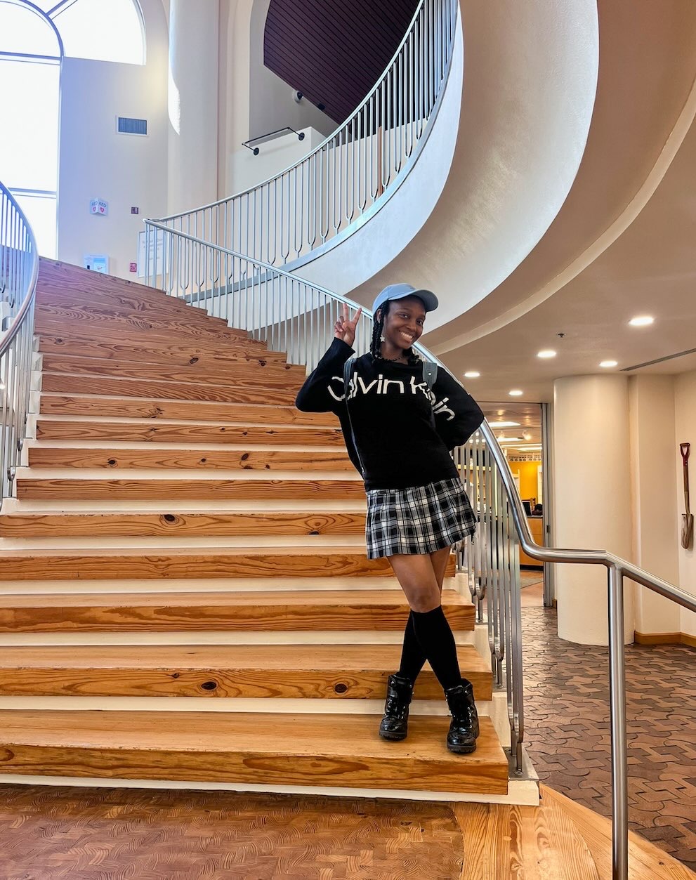 Young woman posing on a staircase inside the African American Museum of Dallas with a peace sign in an open, airy space, as featured in African American Museum of Dallas reviews.