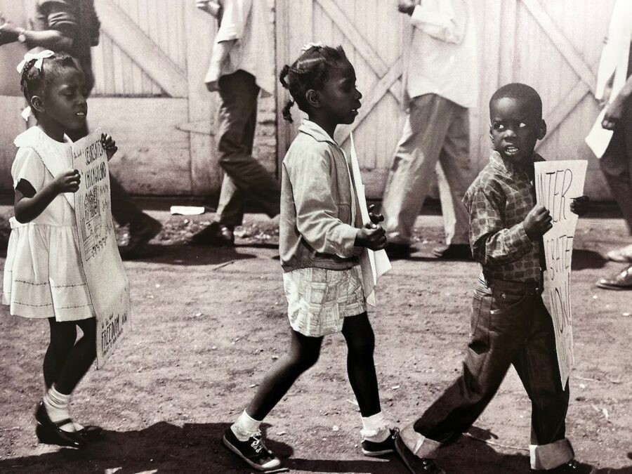 Young boy and two young girls marching with protest signs in a civil rights demonstration, featured in African American Museum of Dallas reviews.