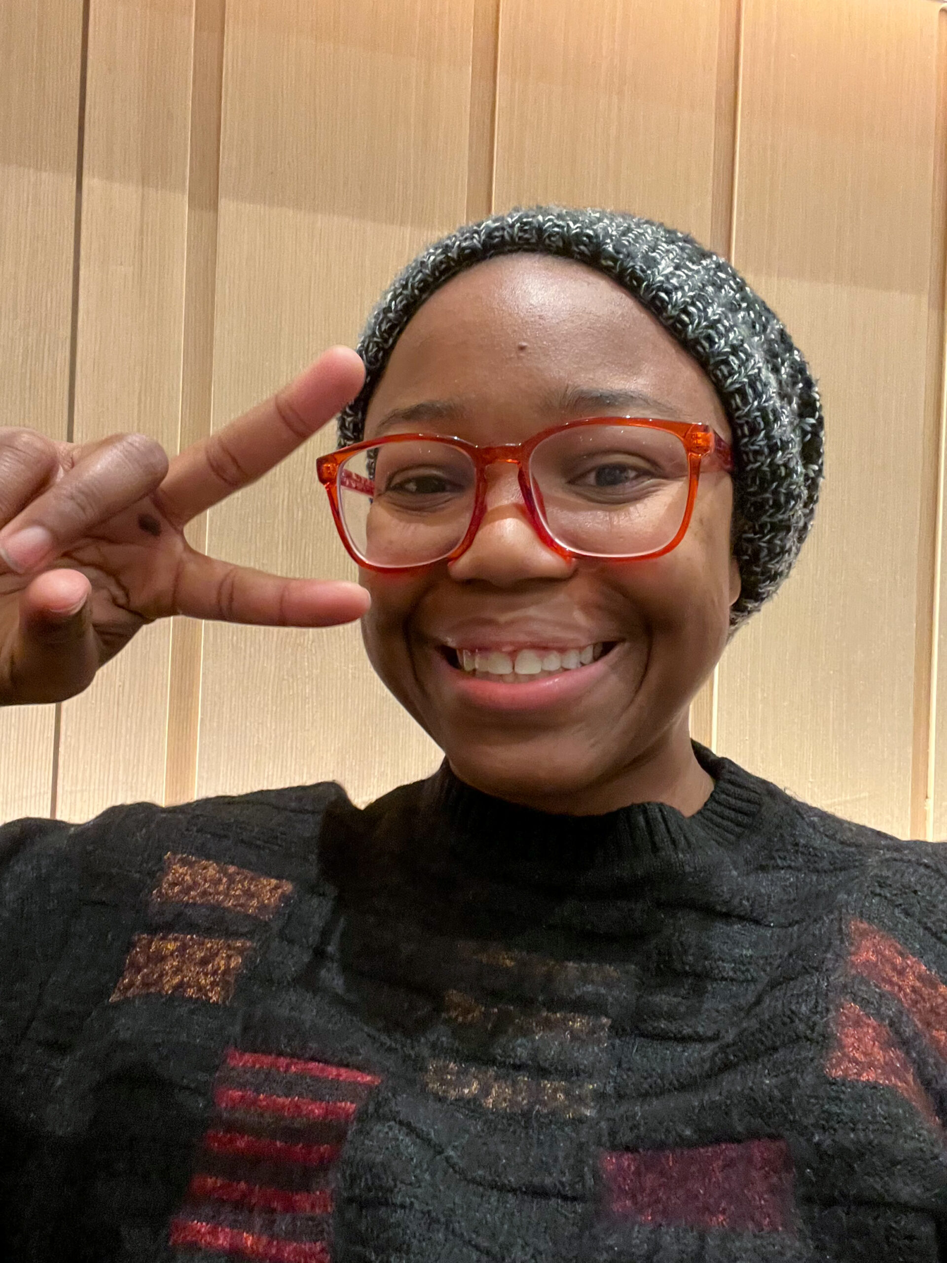 Young woman smiling and making a peace sign inside one of the Dallas airport lounges at DFW Airport.