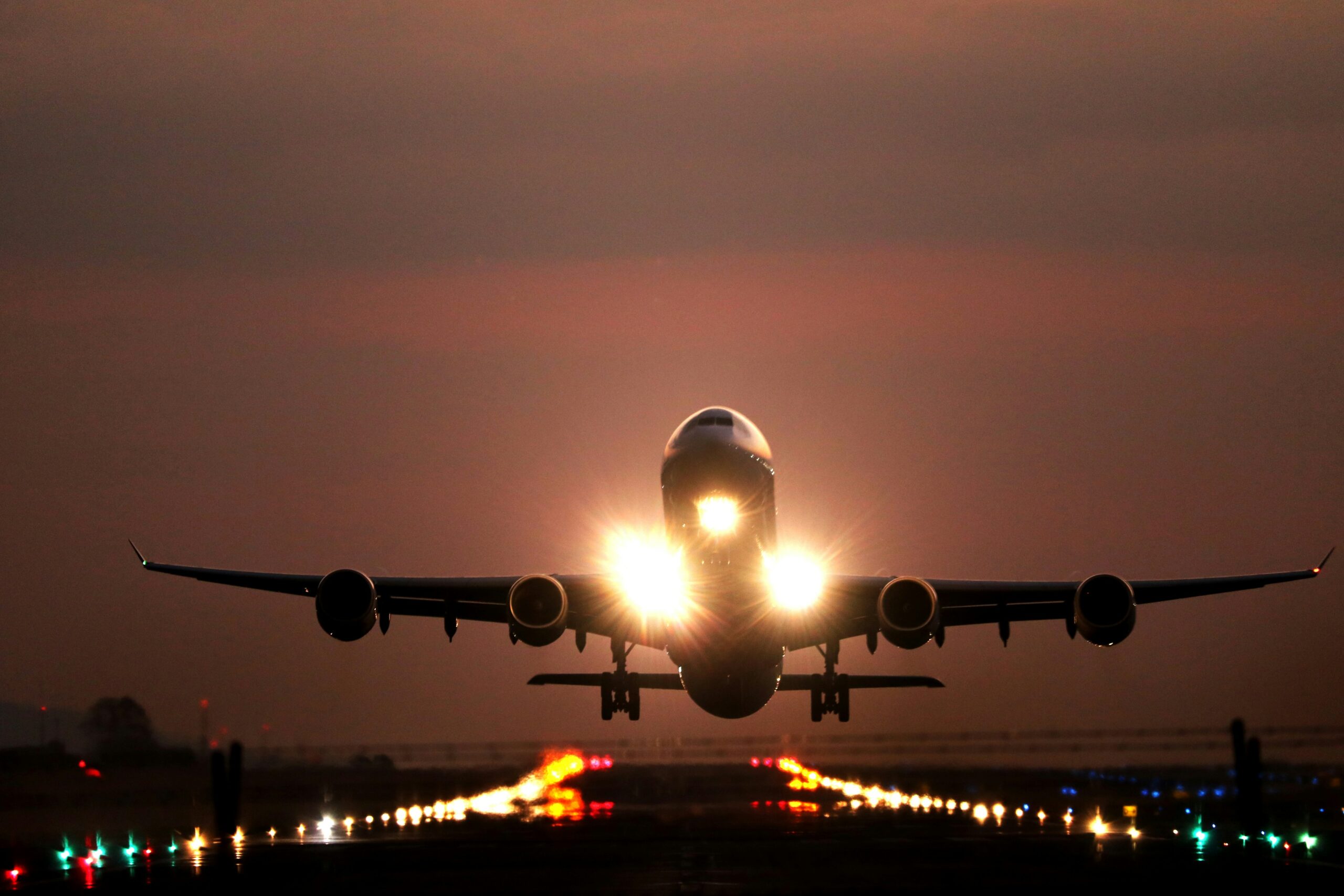 Airplane taking off at dusk with glowing runway lights near Dallas airport lounges at DFW Airport.