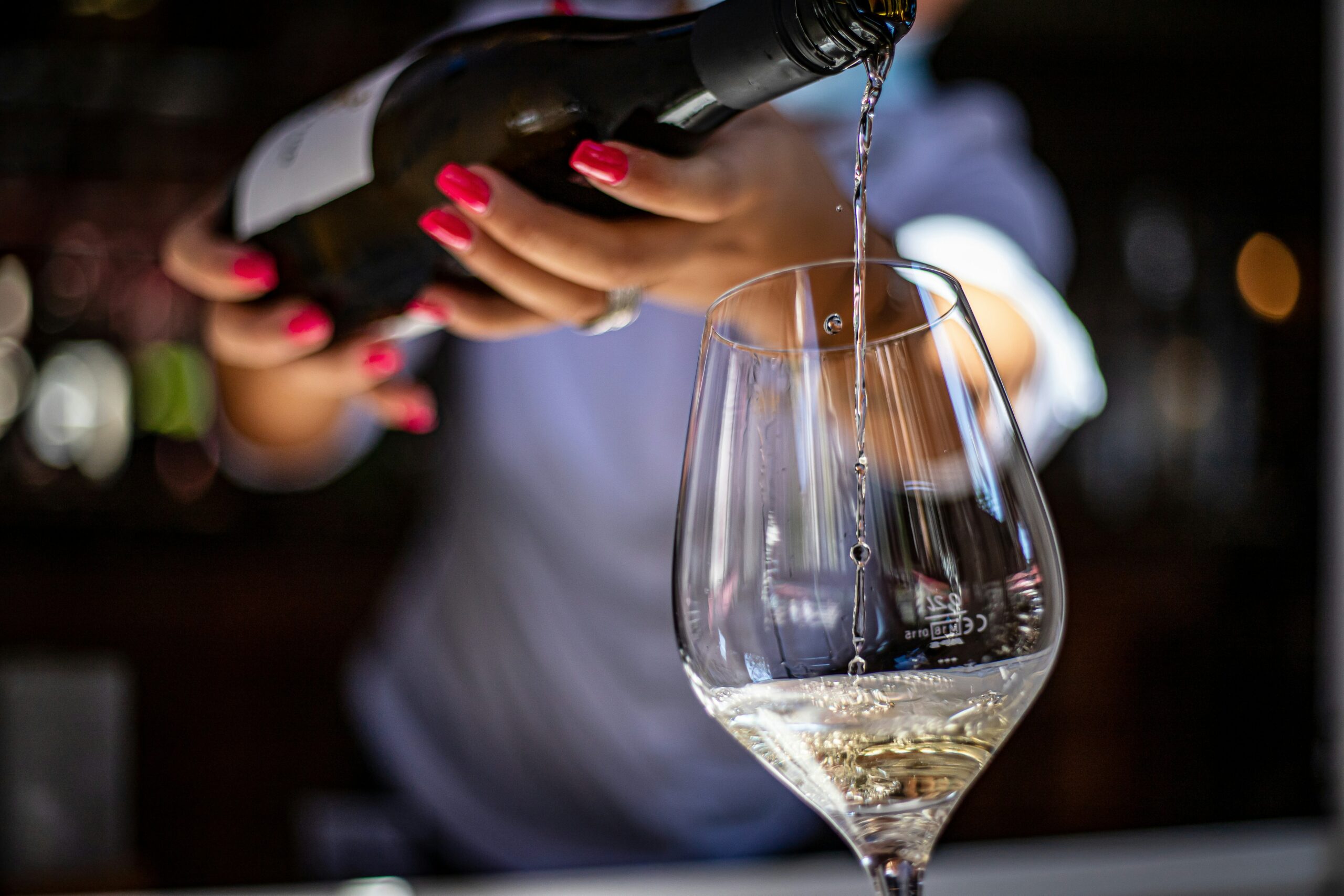 Bartender pouring a glass of wine inside a stylish Dallas airport lounge at DFW Airport.