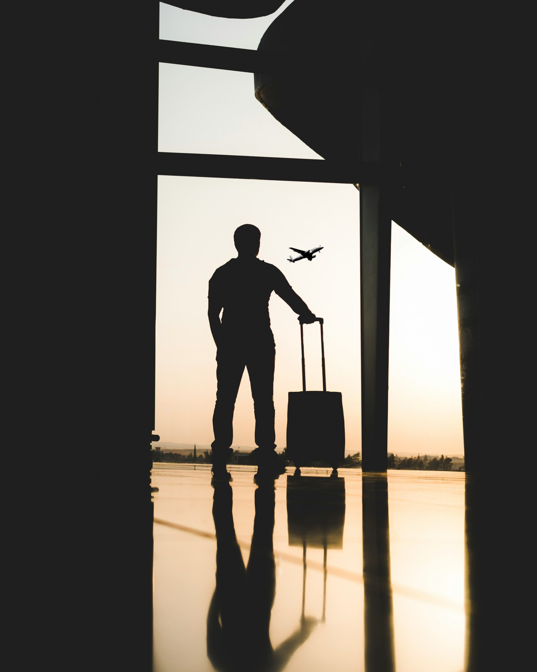 Silhouette of a young man looking out airport windows inside a relaxing lounge space at one of the Dallas airport lounges.