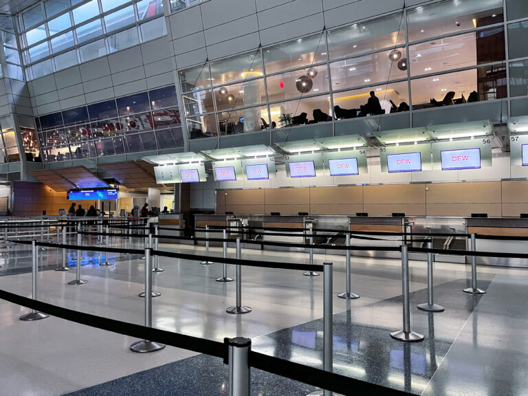 Ticketing counters and queue line markers in Terminal D at DFW Airport, where travelers check in before exploring Dallas airport food options and departing flights.