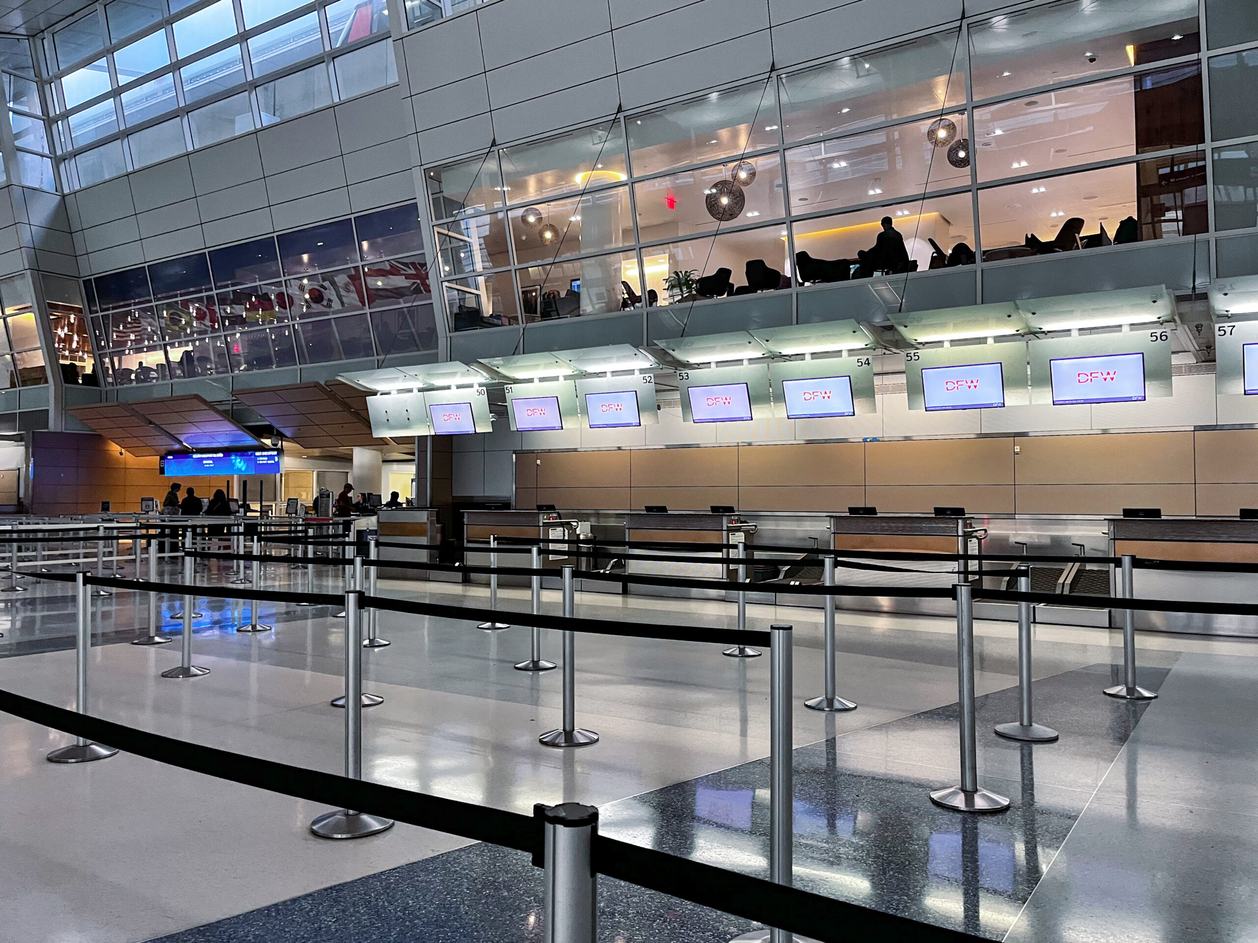 Ticketing counters and queue line markers in Terminal D at DFW Airport, where travelers check in before exploring Dallas airport food options and departing flights.