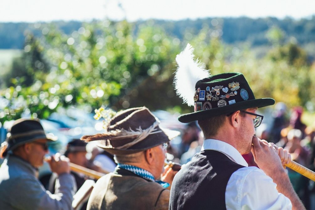 Musicians in hats play wind instruments in parade formation at Oktoberfest Dallas.