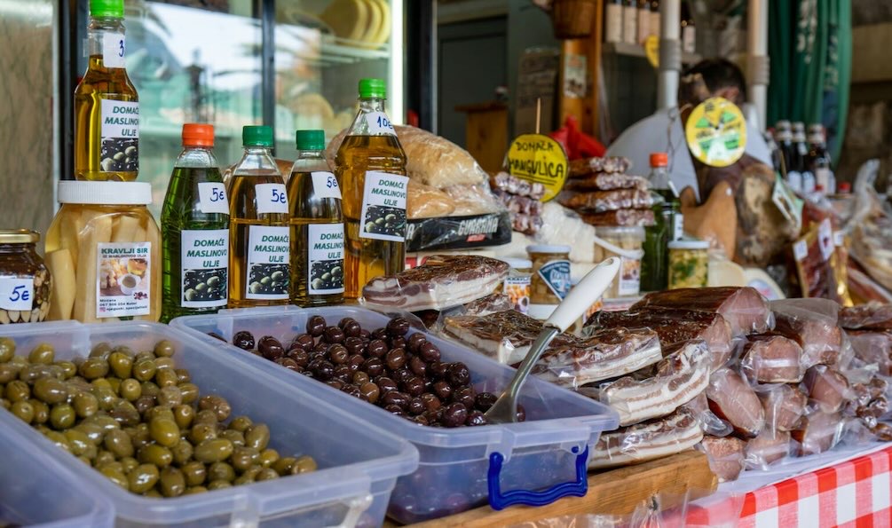 Trays of green and black olives with Greek foods at the Greek Food Festival of Dallas vendor booth.