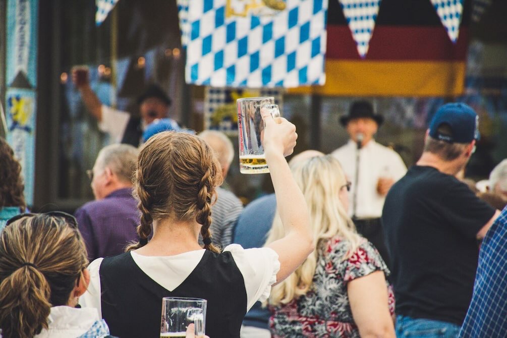 Young woman lifts a stein in a crowd at the Addison Oktoberfest.