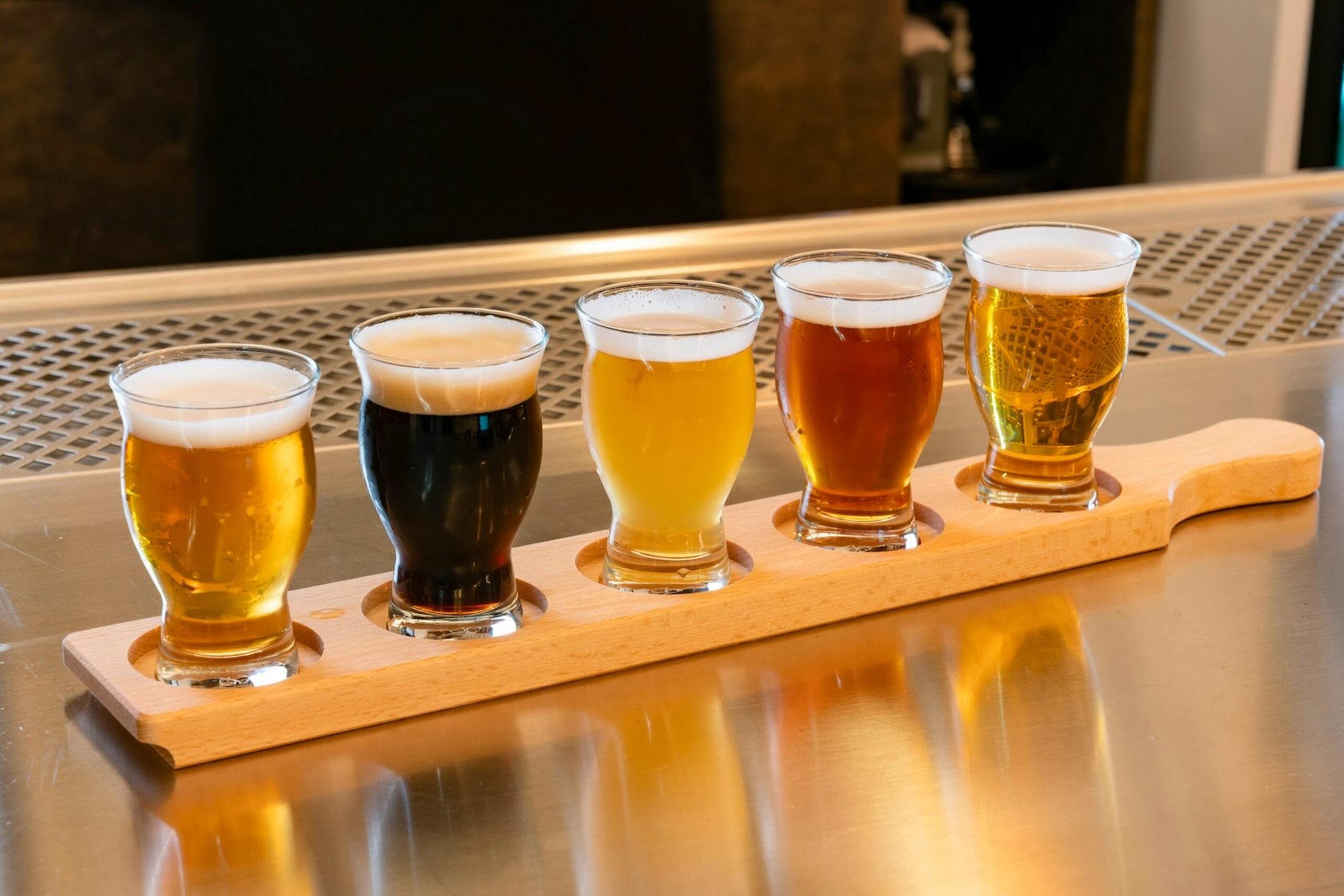 Five beers in a wooden carrier showing a gradient from dark to light beer at  Dallas Brew Festival.