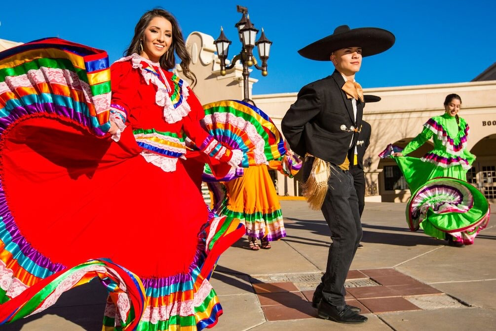 Dancers in colorful traditional costumes perform in an open plaza at one of many Dallas fall events.