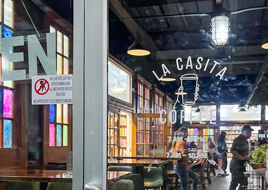 Glass entrance door to La Casita Coffee inside Half Price Books with business hours displayed during a visit to one of the late-night coffee shops in Dallas.