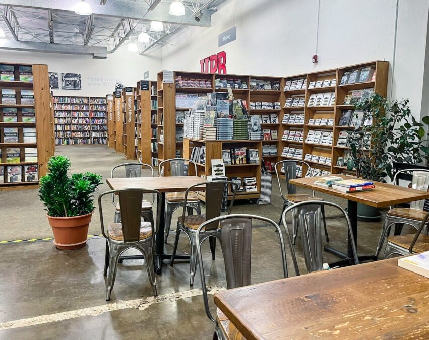 Tables and chairs at La Casita Coffee Shop and Bookstore, surrounded by bookshelves in a cozy, inviting setting.