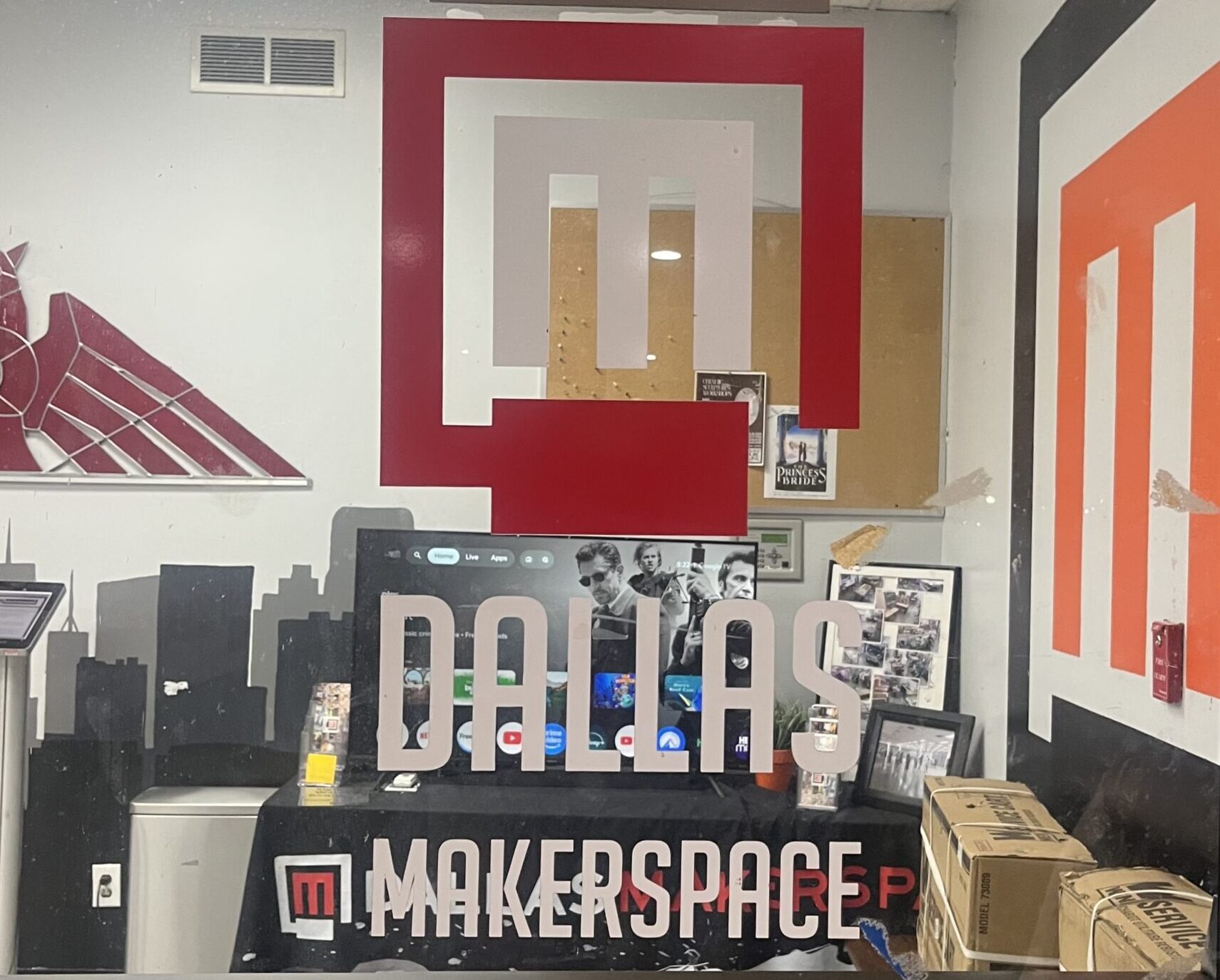 Dallas Makerspace entrance with a view inside at workstations filled with tools and creative materials.