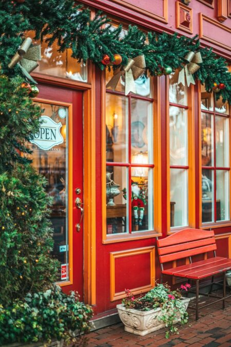 Festively decorated storefront with garland, gold bows, Christmas ornaments, and a bench outside during Christmas in Grapevine.