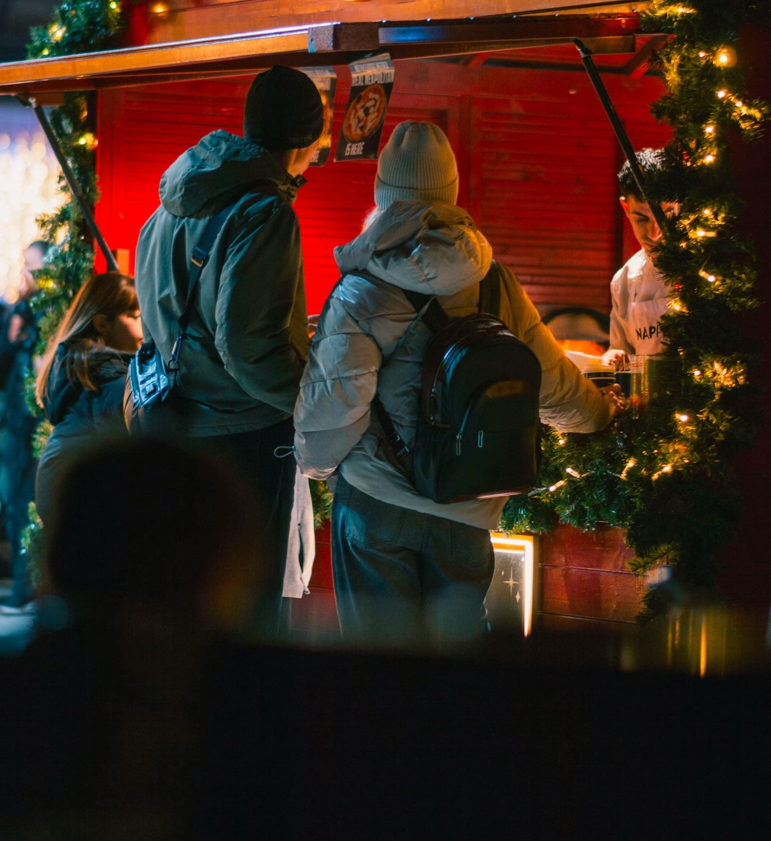 Couple wearing stocking caps and coats wait at an outdoor food both counter during Christmas in Grapevine.