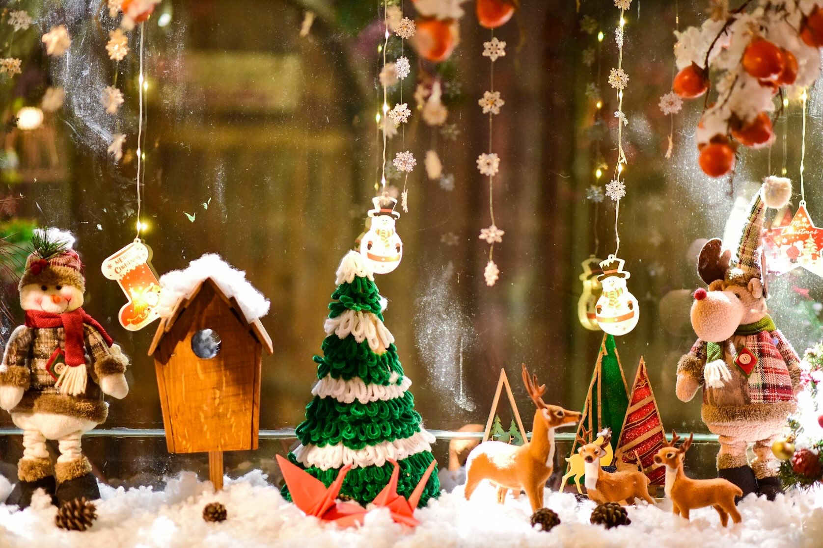 A festive holiday shop window displays handcrafted ornaments in a snowy scene during Christmas in Grapevine.