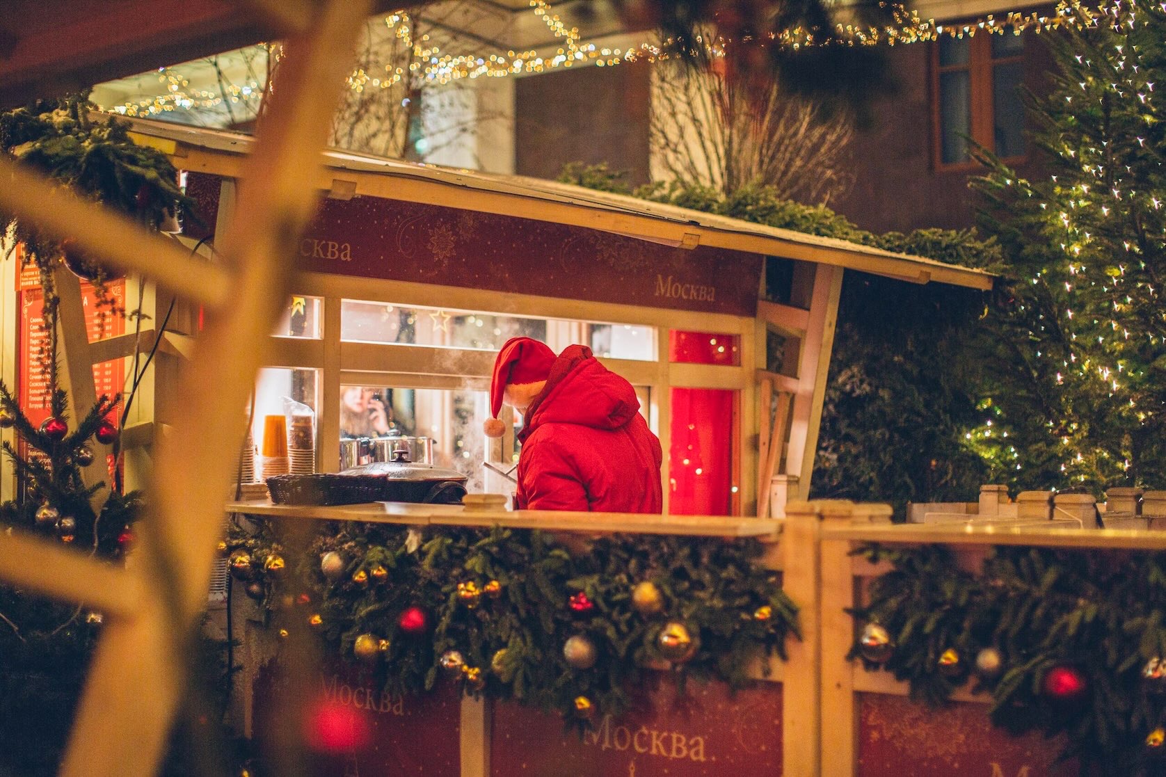 Holiday visitor wearing a red Santa hat and red jacket orders coffee at an outdoor booth during Christmas in Grapevine.