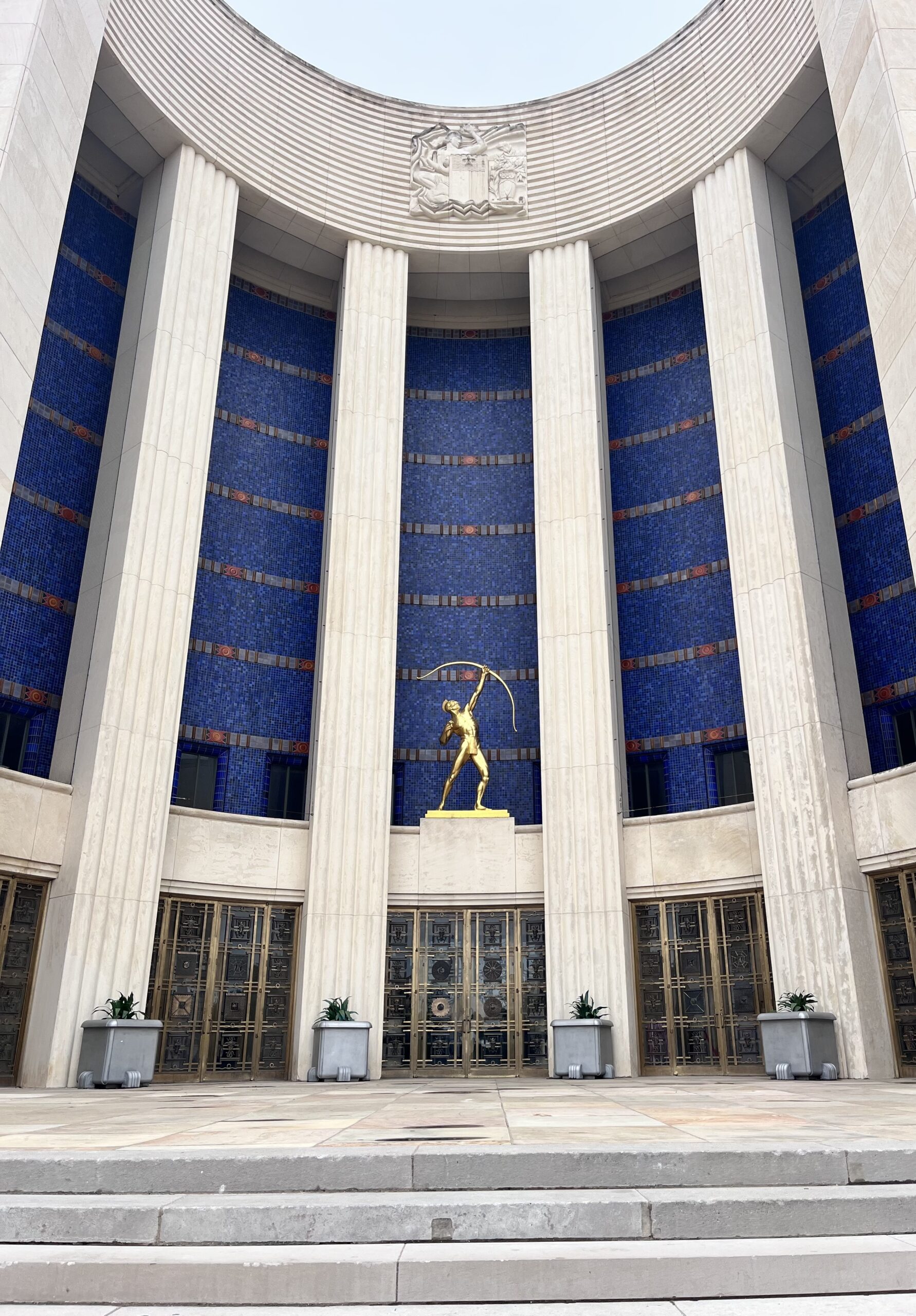 The Tejas Warrior sculpture stands above the Hall of State at Fair Park, its raised bow pointing toward the Symbolic Seal of Texas, a unique-things-to-do-in-dfw landmark.