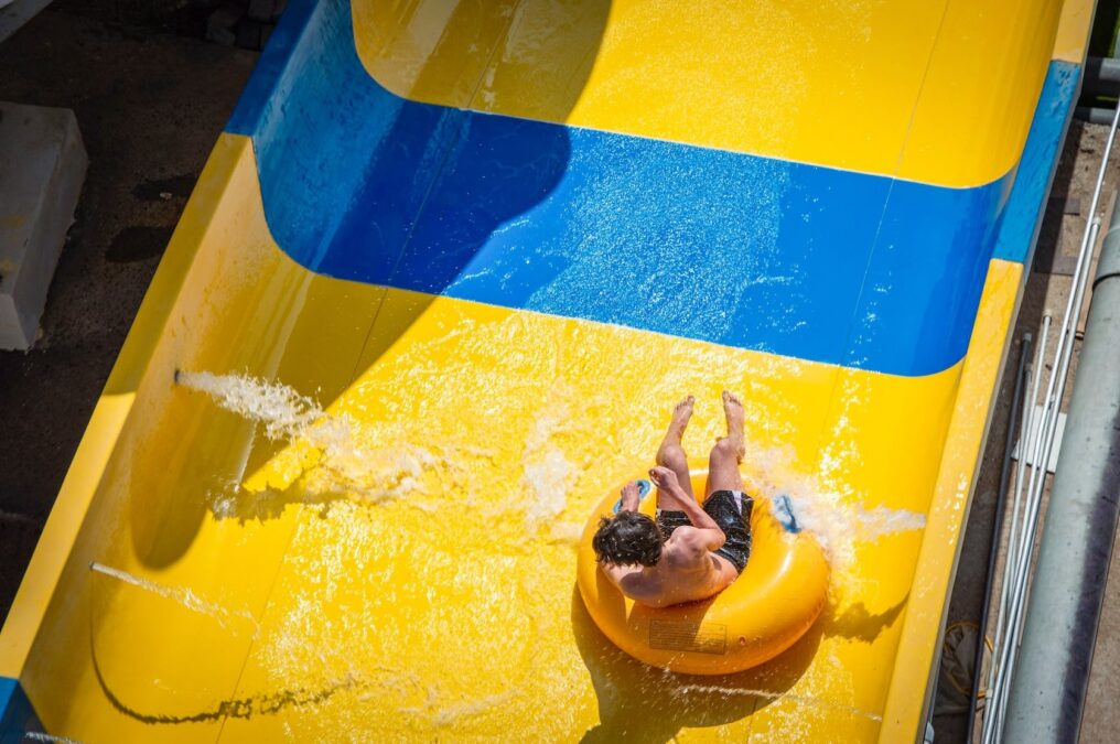 Young man racing down a waterslide at Great Wolf Lodge in Grapevine during Snowland, a festive winter in Dallas holiday attraction.