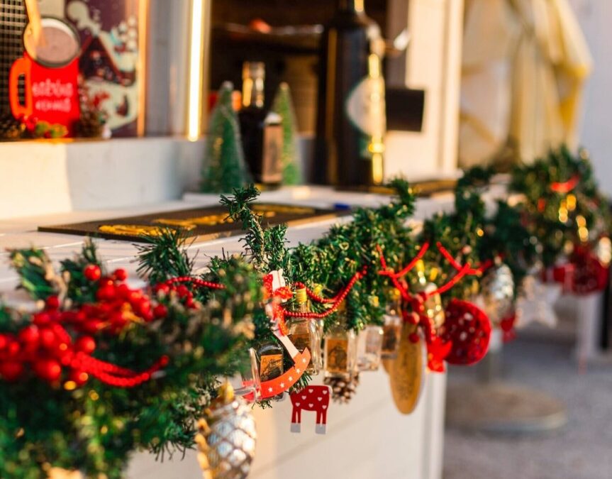 Winter in Dallas festive Christmas counter decorated with green trim, red looped beads, hanging ornaments, Christmas figures, and holly.